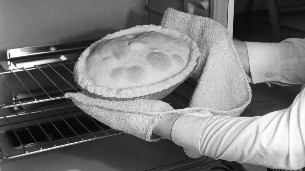 A pie is placed in a gas cooker, 1st March 1963.