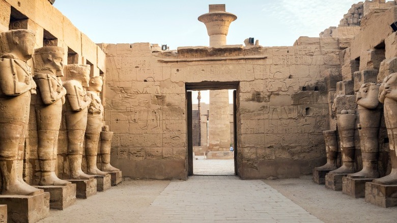 The temple of Karnak with tall statues lining the pathway 