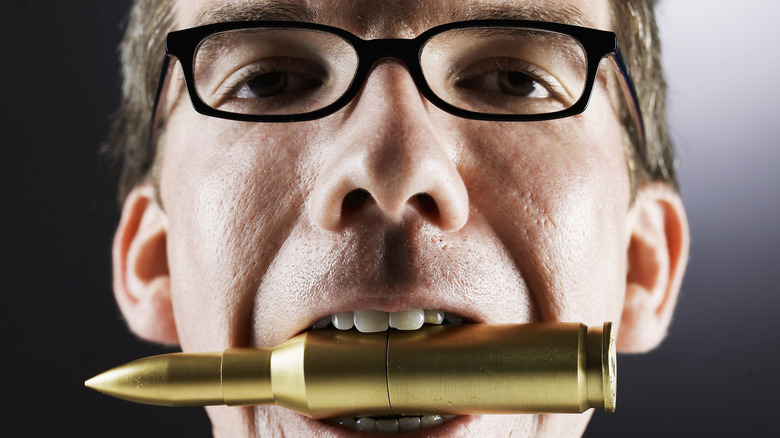 Man biting a very large bullet