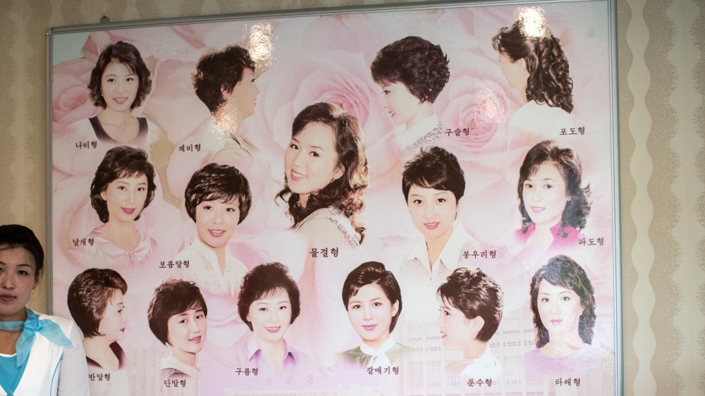 Woman standing by poster of North Korean hairstyles