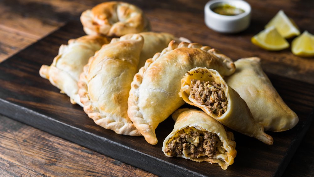 Traditional baked Argentine empanadas savoury pastries with meat beef stuffing against wooden background