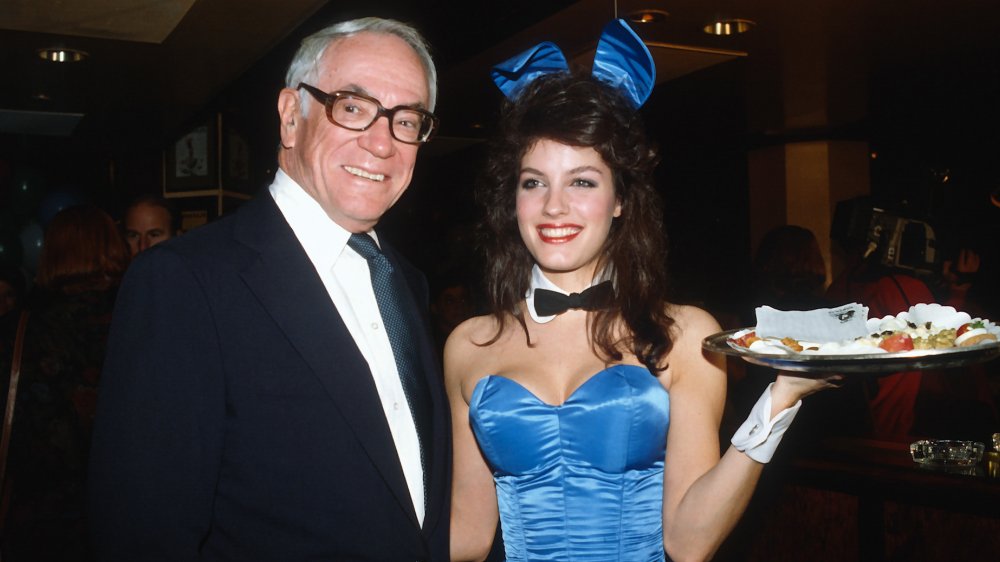 Malcolm Forbes next to Playboy Bunny holding a food tray