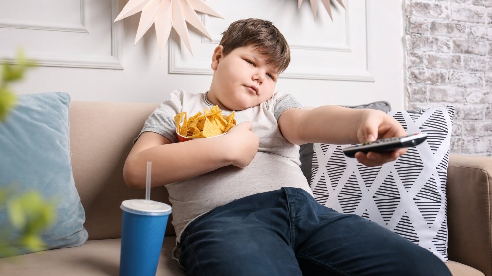 Boy slouched on couch, presumably watching the day's stock market.