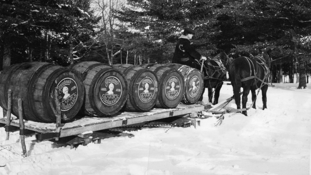Vats of mollasses being delivered by horse-drawn sled