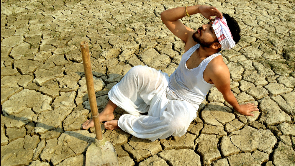 Distraught Indian farmer sitting in his parched field