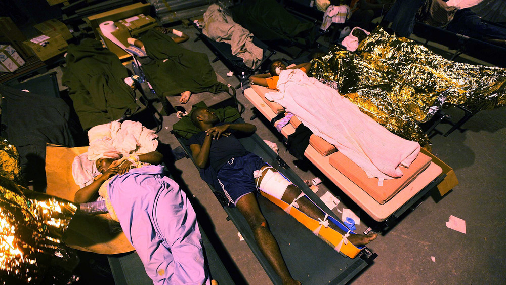 JANUARY 13: Injured people are seen at a makeshift field hospital on January 13, 2010 in Port-au-Prince, Haiti. 