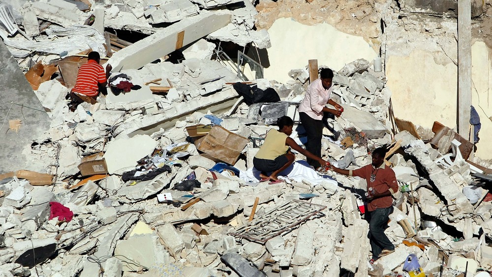 People pick through the rubble of their home after a massive earthquake destroyed it on January 14, 2010 in Port-au-Prince, Haiti.