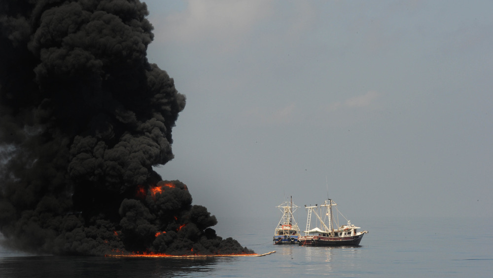 GULF OF MEXICO - MAY 6 : Two fishing vessels drag an oil boom after trapped oil is set ablaze May 6, 2010 in the Gulf of Mexico