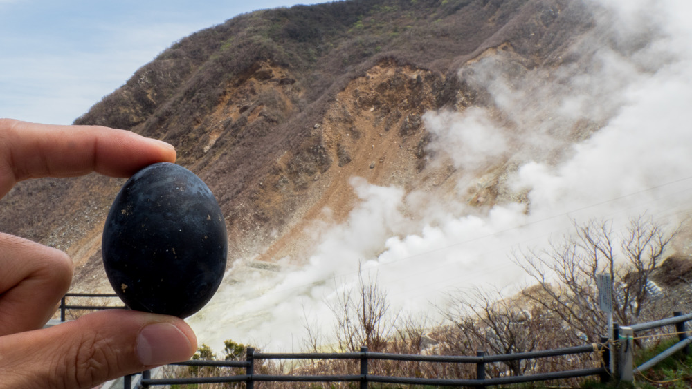 A black egg of Owakudani held in front of the mountain's onsen