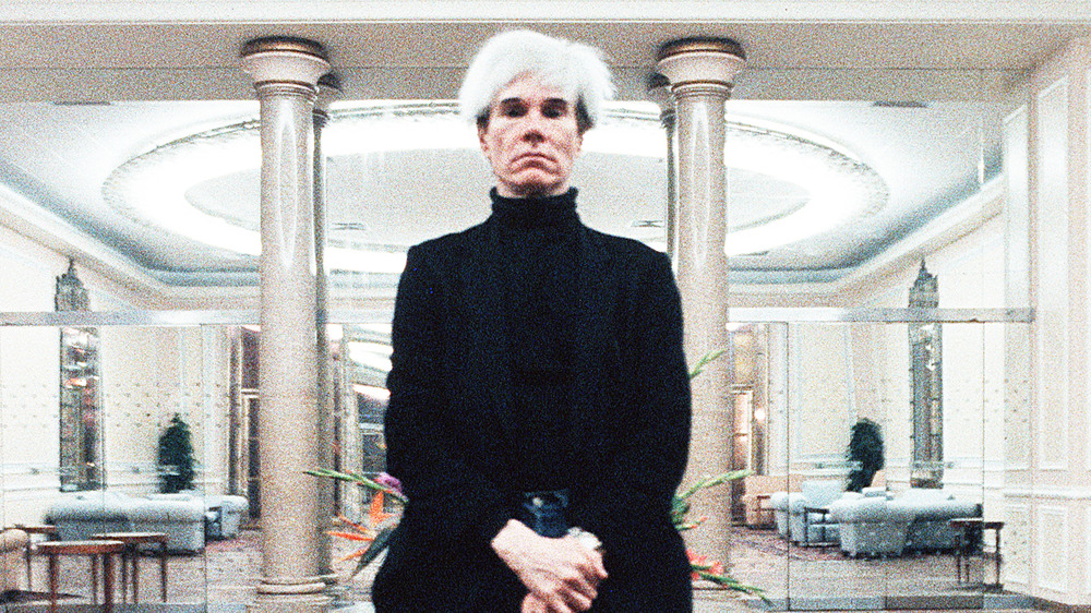 Andy Warhol stands flanked by columns