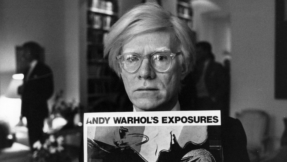 Andy Warhol holding a poster