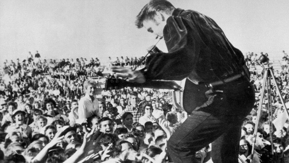 Elvis performing on stage to a crowd of excited fans on an outside stage
