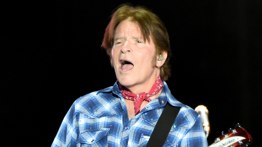 John Fogerty singing in blue plaid shirt