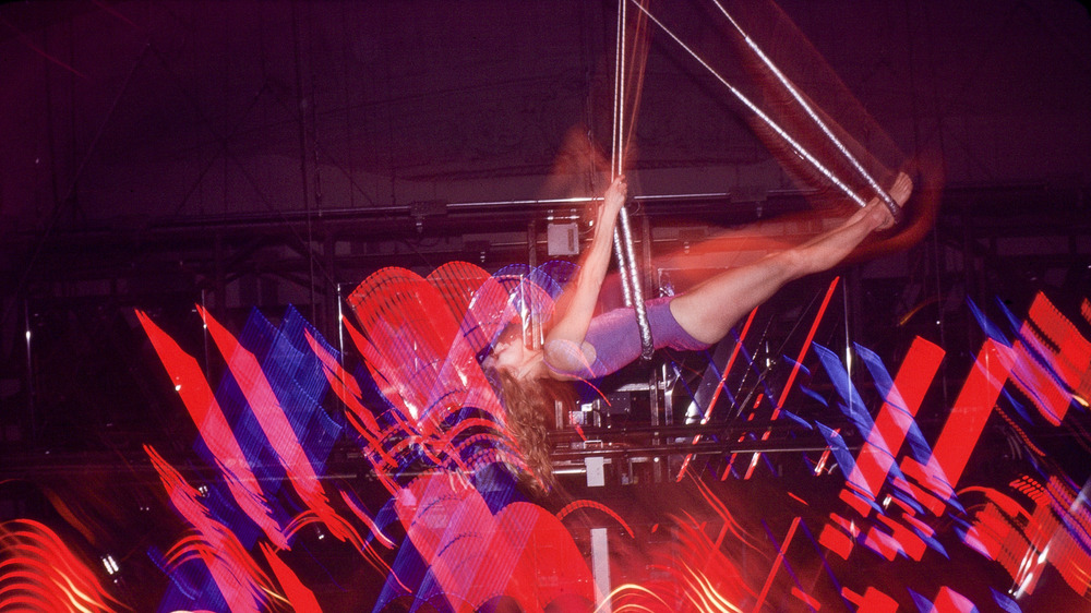 dancer swinging in air above lights