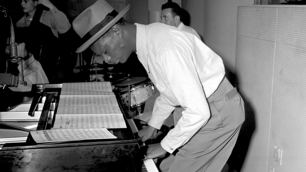 Nat King Cole stands to play the piano