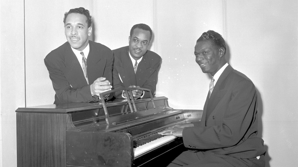 The King Cole Trio posing for a photo by the piano