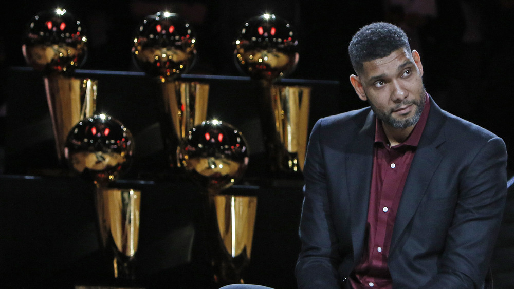 Tim Duncan in front of trophies 
