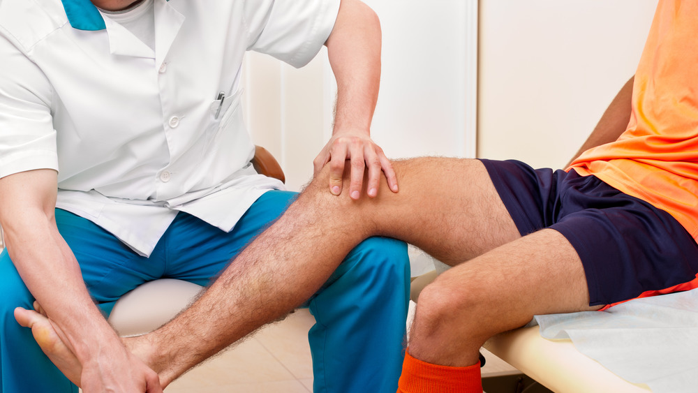 Doctor observing athlete's leg injury