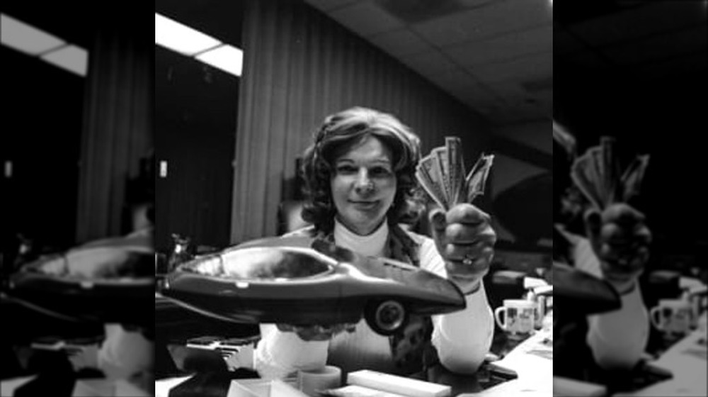 Elizabeth Carmichael posing with cash and a model car