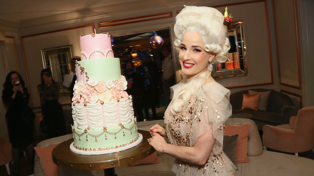 Dita Von Teese posing next to a cake