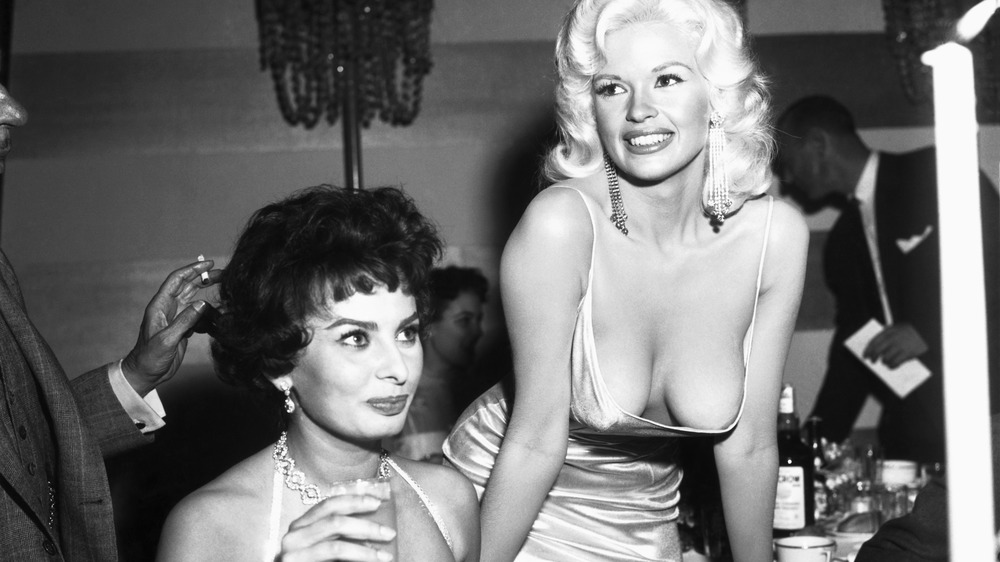 Sophia Loren seated and looking ahead, with Jayne Mansfield standing above