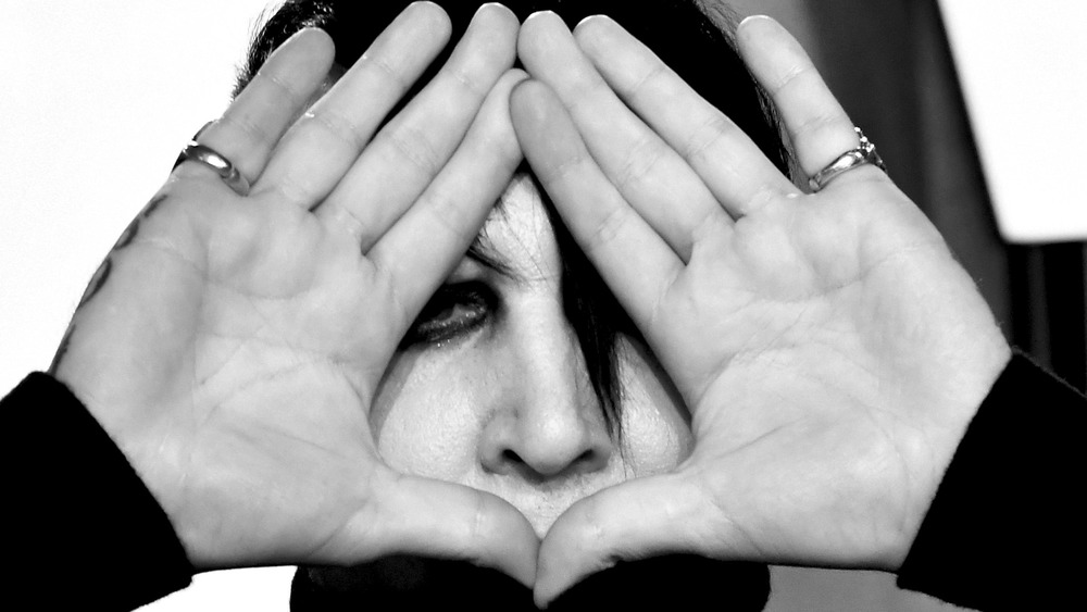 musician Marilyn Manson covering his face with his hands