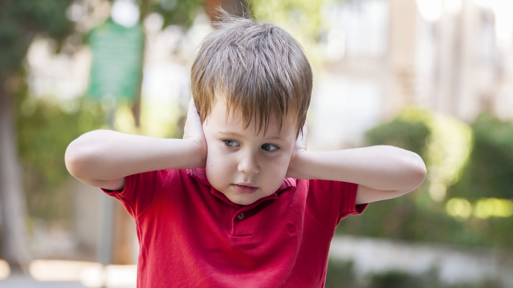 boy with hands over ears