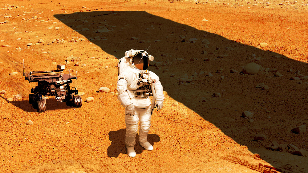 An astronaut beside the shadow of a monolith