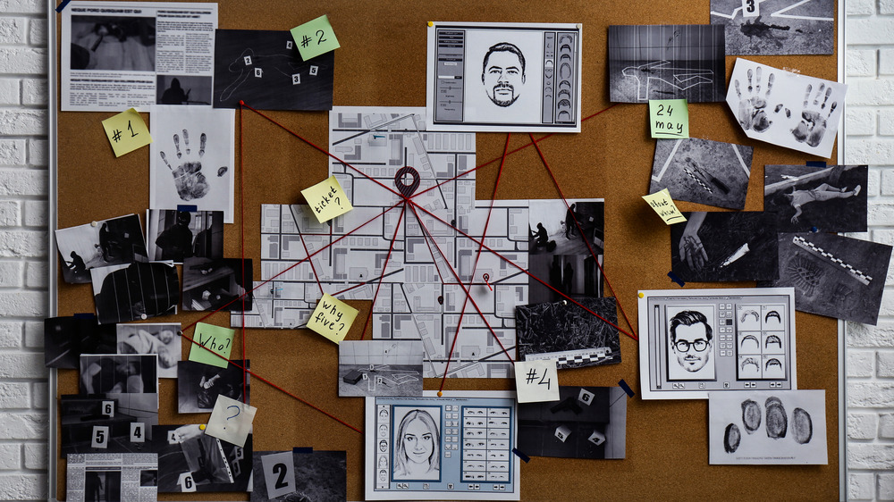 A board with pictures and documents connected by red string