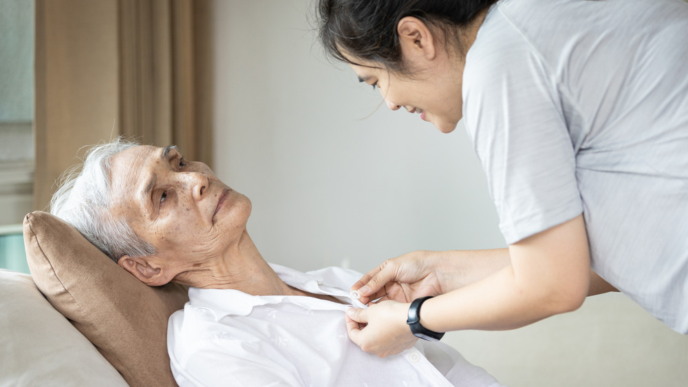 Woman dressing paralyzed patient 