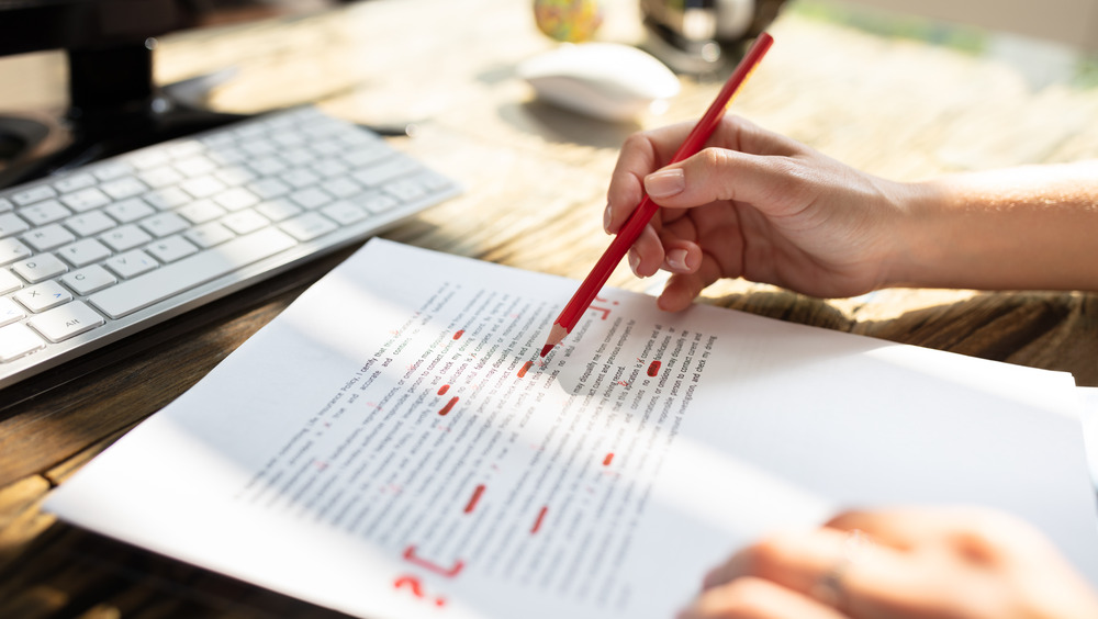 Hand editing paper with red pencil