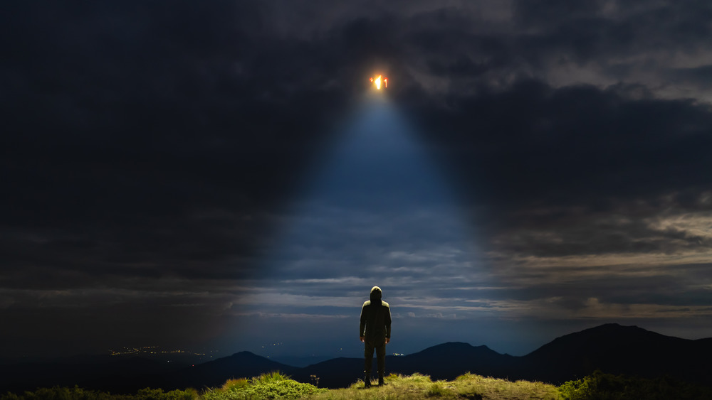 Man standing beneath UFO beam