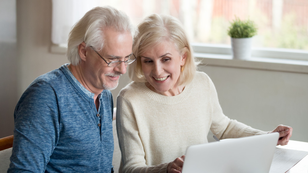 Happy middle-aged couple looking at laptop