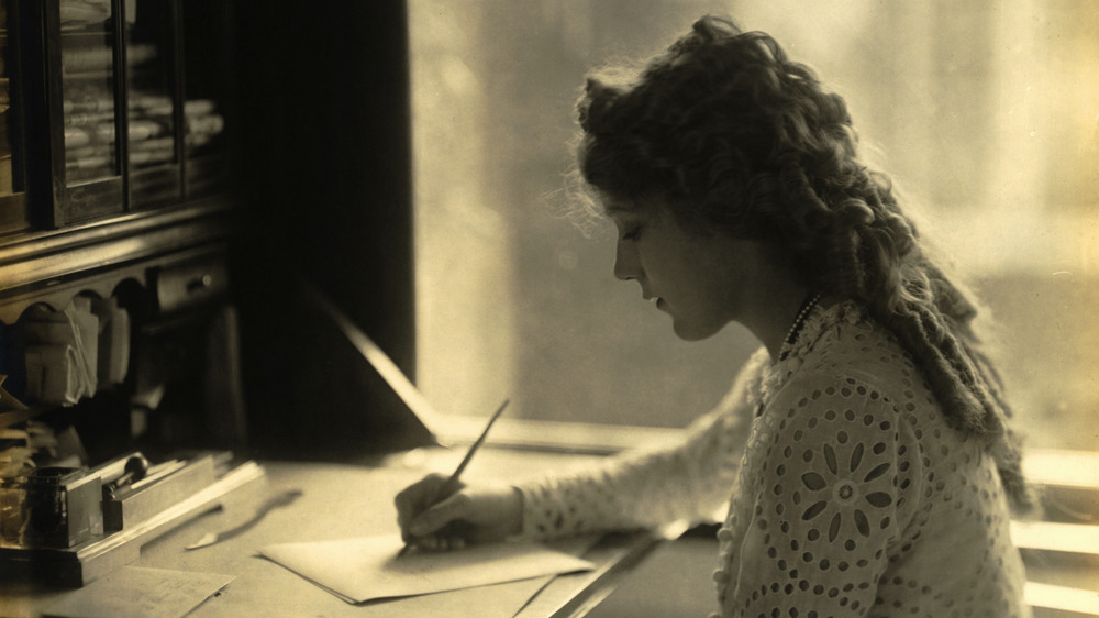 Mary Pickford writing at a desk., Mary 23, 1918