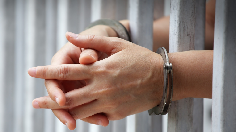Handcuffed hands behind bars