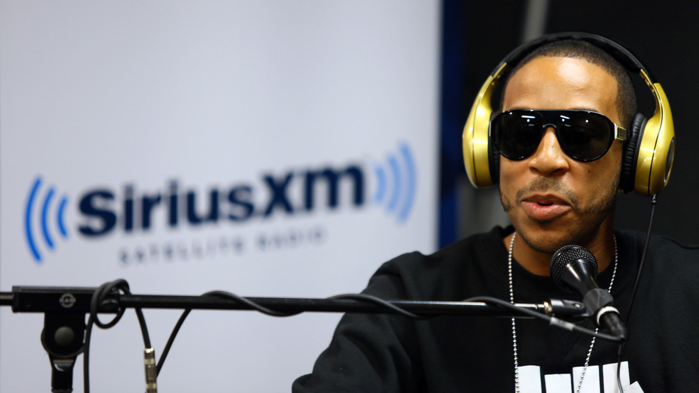 Ludacris sitting with headphones on in front of a mic 