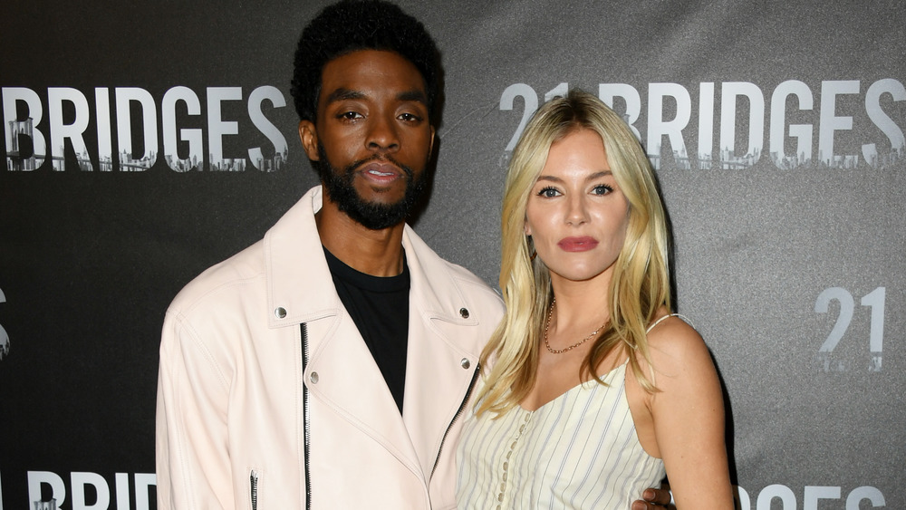 Sienna Miller smiling with Chadwick Boseman