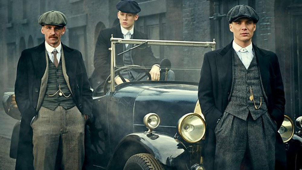 The Peaky Blinders in front of a car