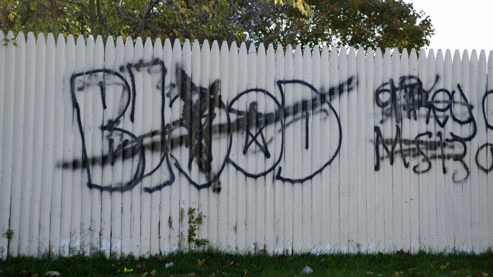 Black grafitti on white fence