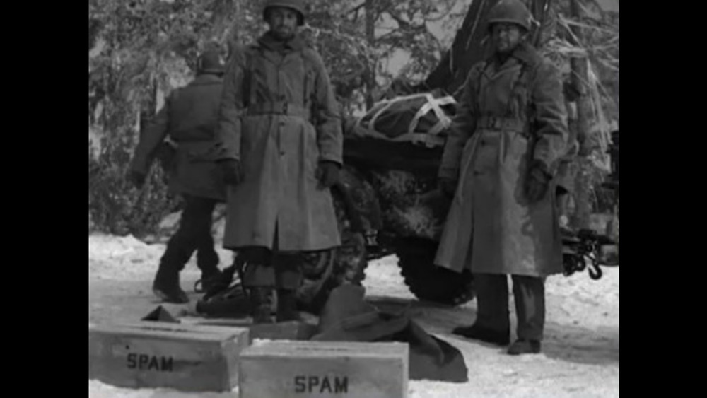 Two soldiers posing with crates of Spam during World War II