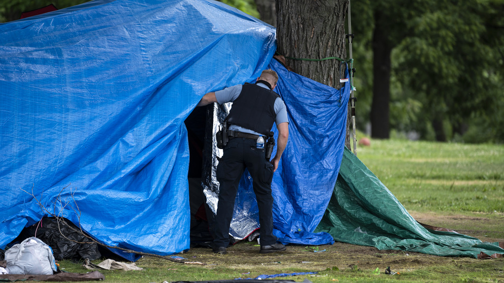 Police officer entering homeless encampment 