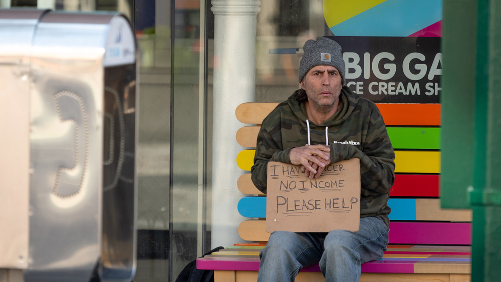 Homeless man panhandling outside ice cream store