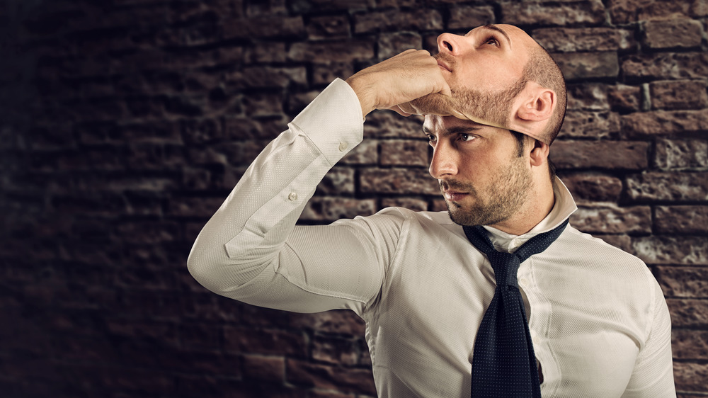 A man removing a mask of his own face