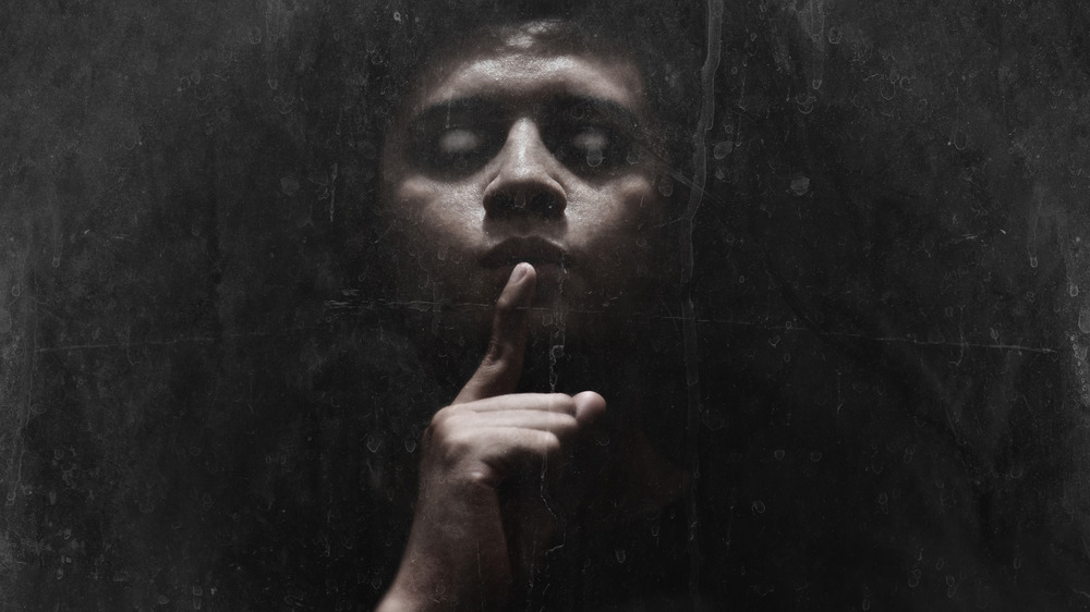 A criminal holding his finger up to his lip