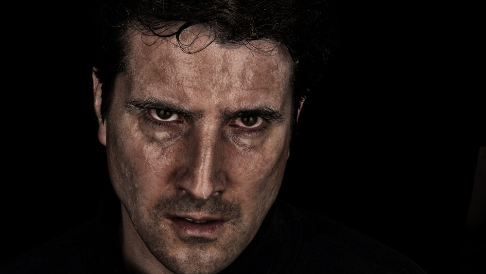 A man with a dark background glaring