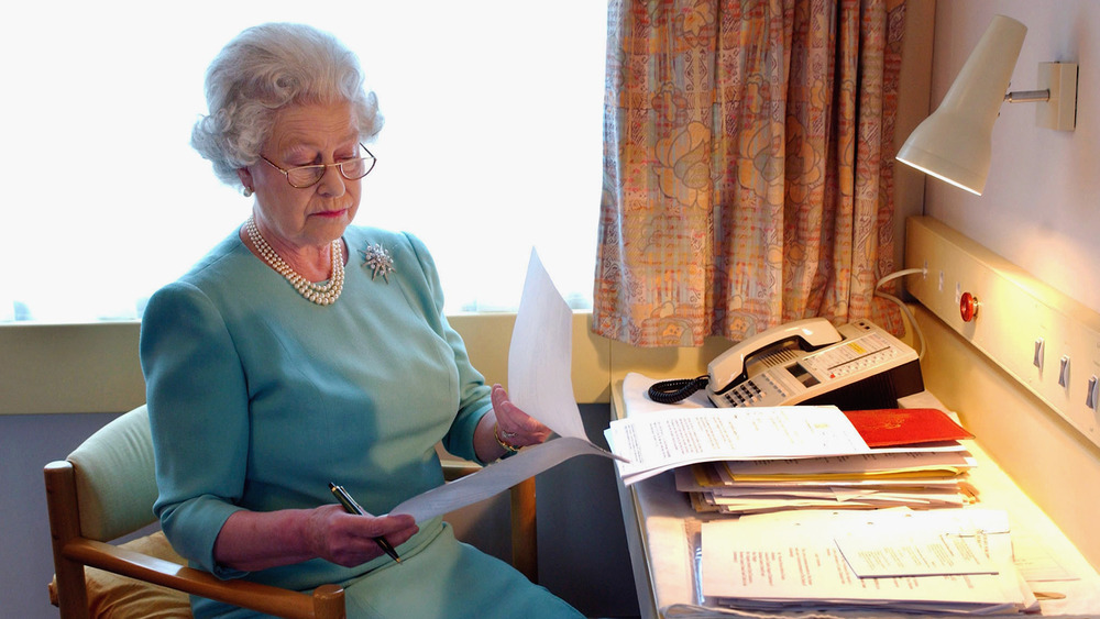 Queen Elizabeth II works at her desk on the Royal Train in May of 2002.