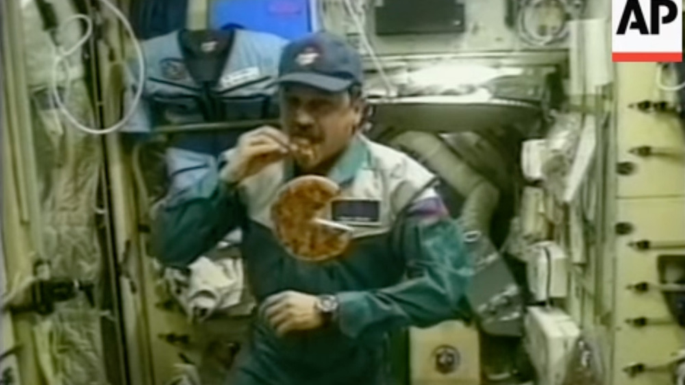 Cosmonaut Yuri Usachov eats a slice of pizza 