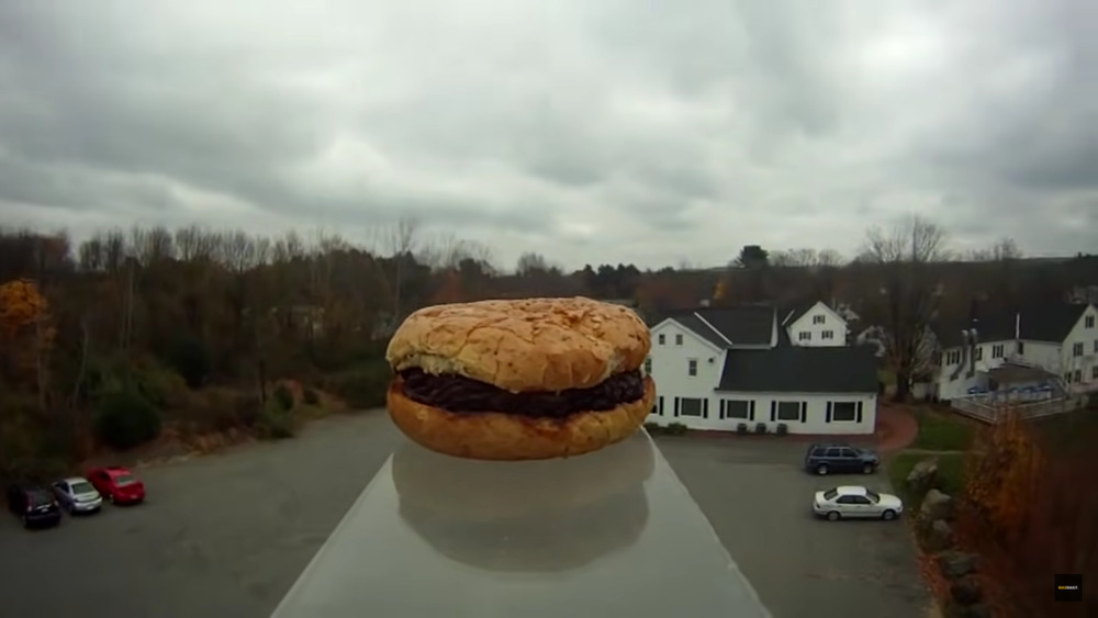 A burger floating up in the air right above a few houses