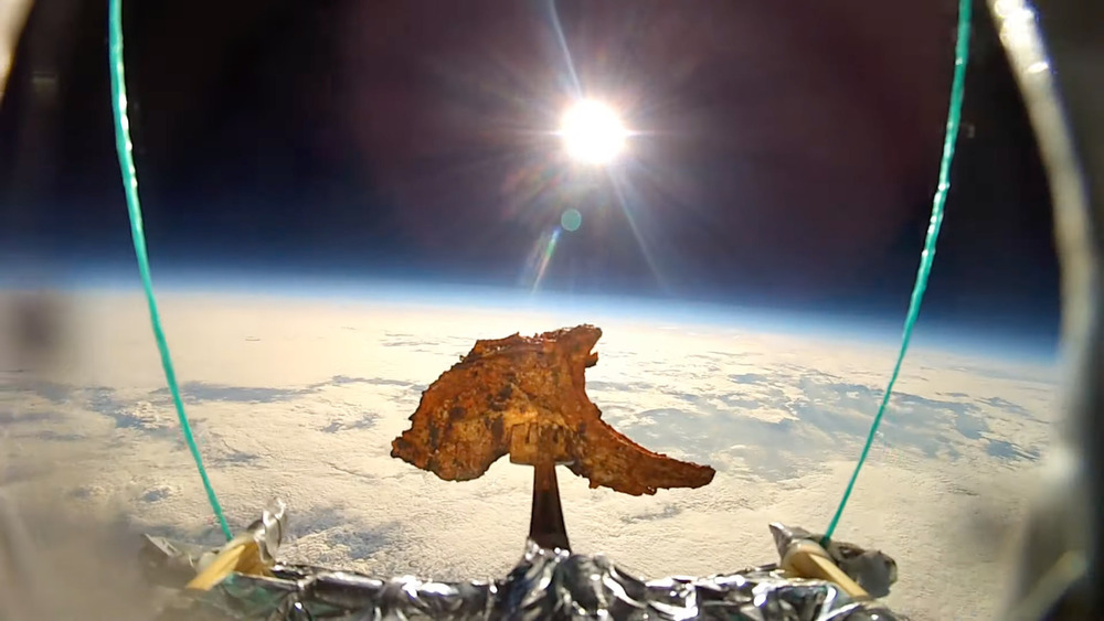A lamb chop on a fork in space above the eart