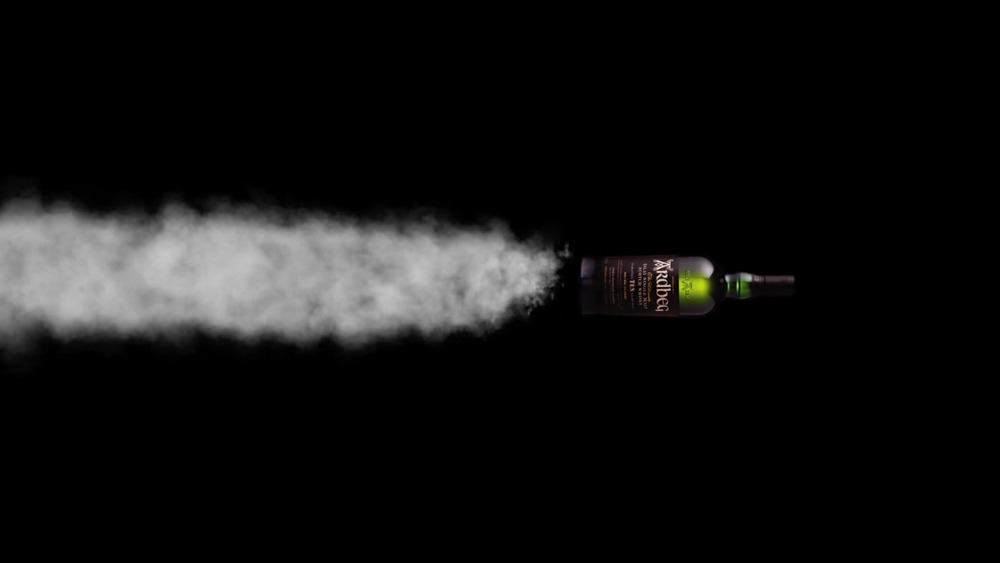 Ardbeg bottle flying horizontally with smoke blowing behind it